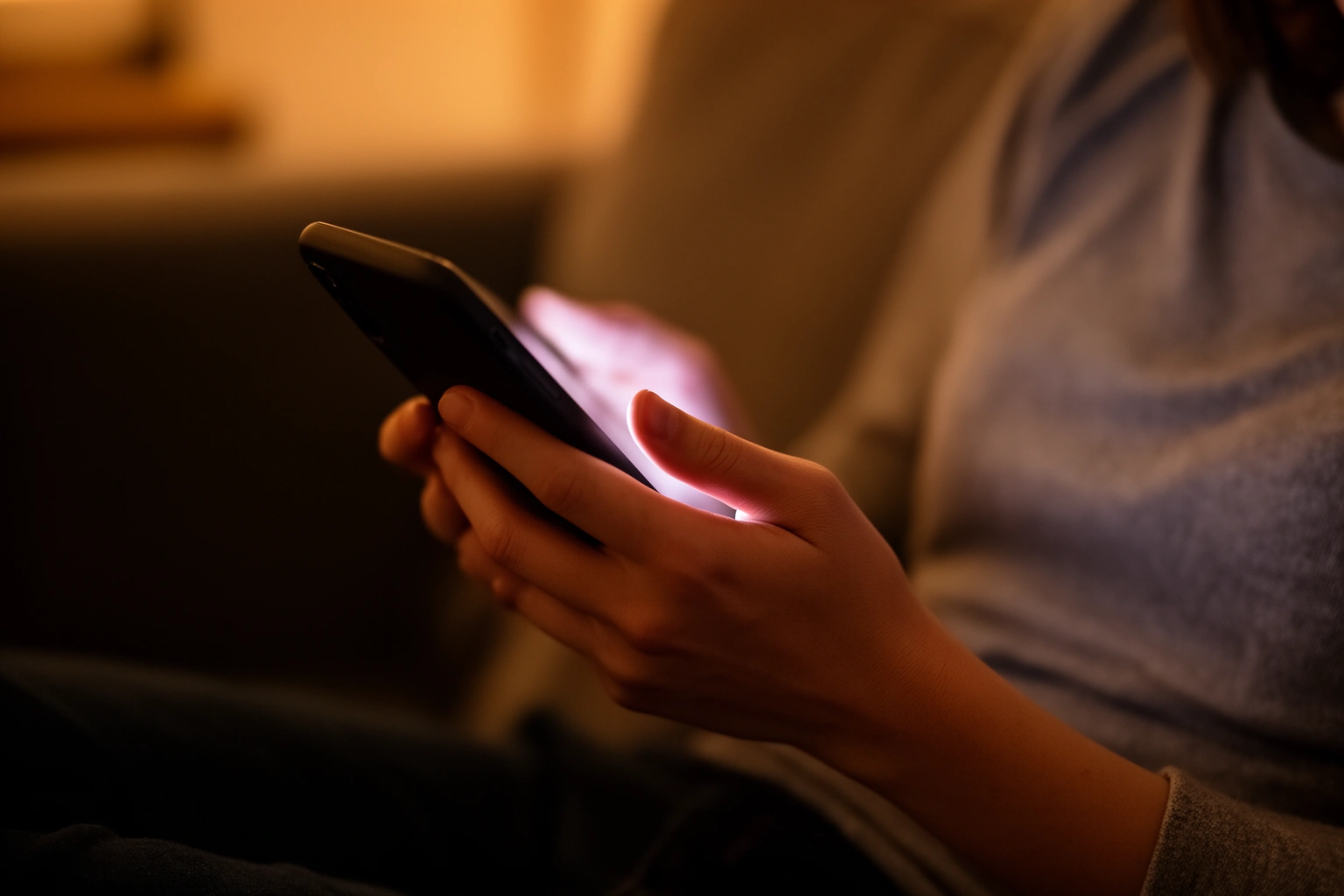 Person looking thoughtfully at a smartphone screen while chatting with an AI assistant, reflecting on emotional connection with technology